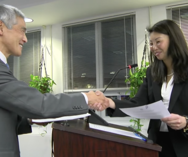 Huang (right) being sworn in by Usami (left). 