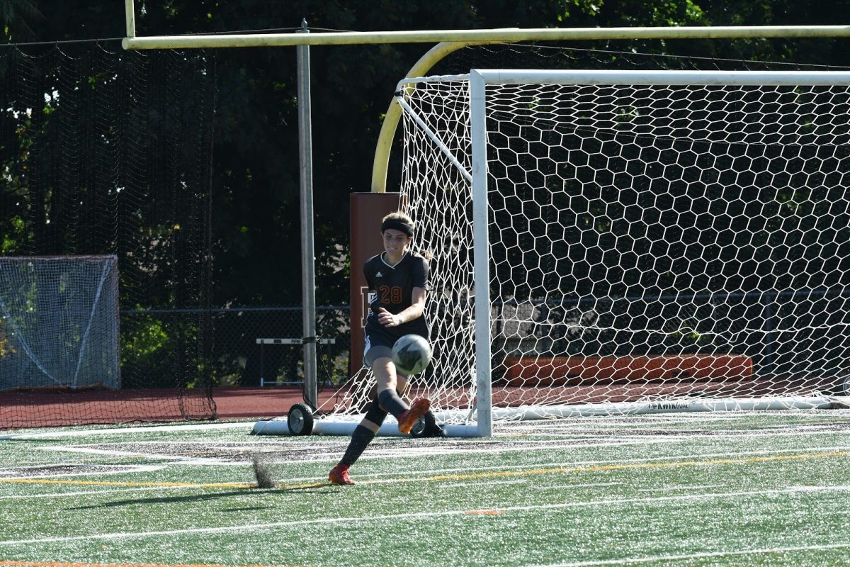 Senior Abbey Roche kicks a goal kick in a girls' soccer game.